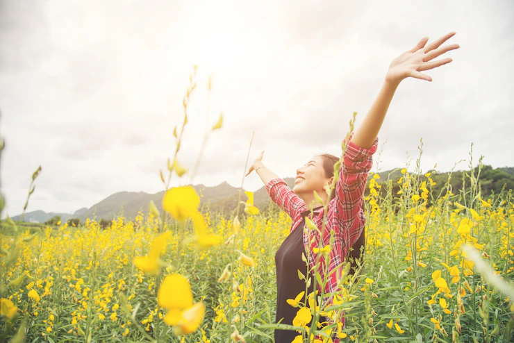 woman raising her hands on fresh yellow cute floral park