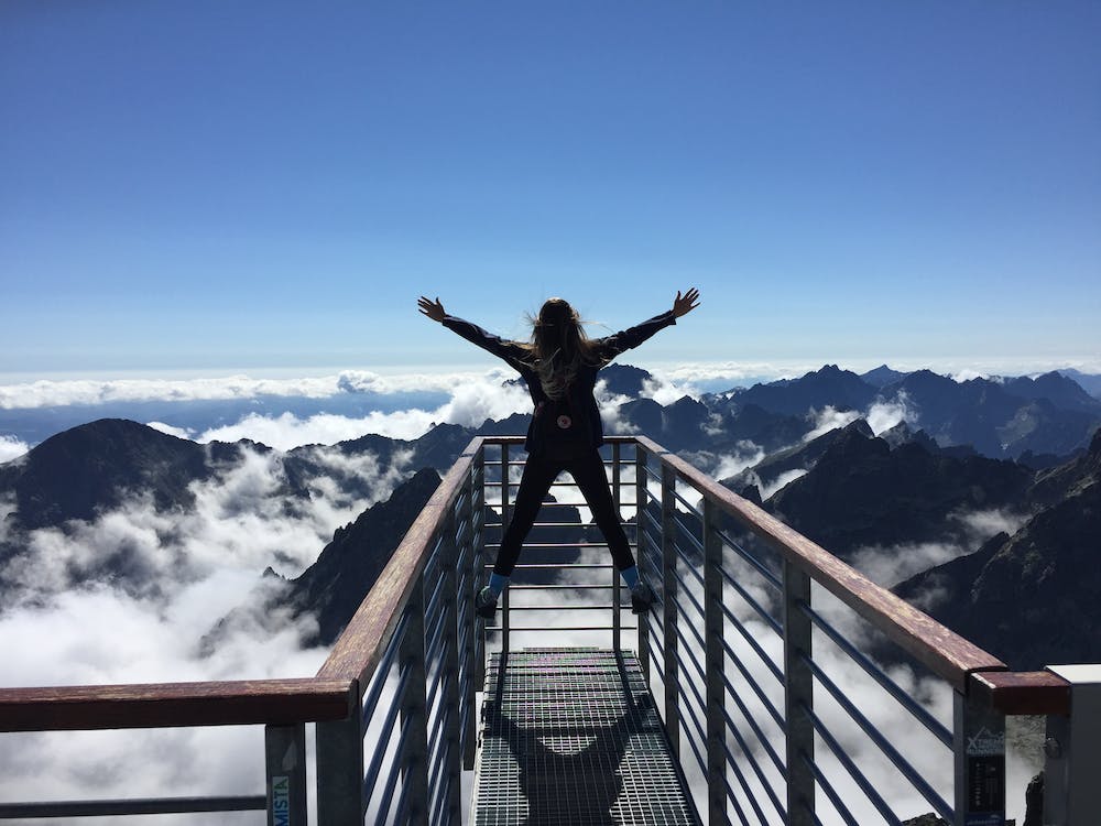 person standing on raising her hand to the mountain